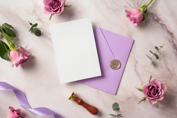 Luxury wedding invitation card mockup with violet envelope, wax seal stamp, roses buds on marble desk table. Flat lay, top view, copy space.