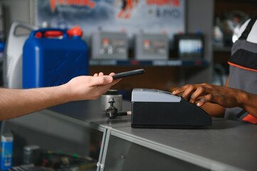 Close up. The buyer pays for the purchase of auto parts through a POS terminal
