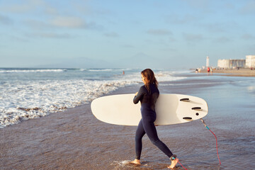 latin women getting into the ocean with surfboard to ride the waves 