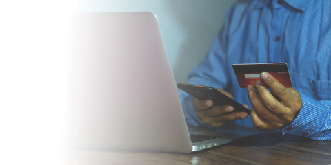 person working with laptop holding smartphone credit debit card for online payment shopping,...