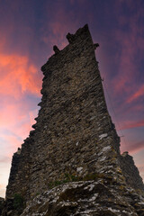 Low-angle view of the remains of the medieval castle in the so-called "village of witches", famous for the witch trials, against a dramatic sunset sky, Triora, Imperia, Liguria, Italy