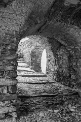 Black and white photo. Uphill stone arcade in the "village of witches", famous for the witch trials dating back to the 16th century, Triora, Imperia, Liguria, Italy