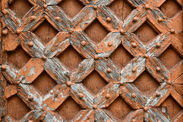 Close-up of an old wooden door decorated with inlays and studs, suitable for background, texture, pattern, etc.