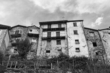 Black and white photo. Low-angle view of medieval houses in the so-called "village of witches", famous for the witch trials dating back to 16th century, Triora, Imperia, Liguria, Italy