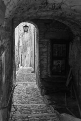 Black and white photo. A narrow alley in the "village of witches", famous for the witch trials dating back to the 16th century, Triora, Imperia, Liguria, Italy