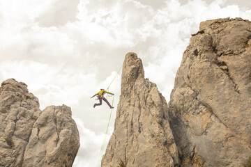 A man is jumping off a cliff with a green rope. Concept of adventure and excitement, as the man is...
