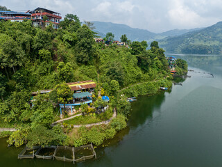 Aerial view of Begnas Lake the third largest lake of Nepal. Wild nature and trees with houses surround the lake, typical Nepalese boats can be seen in the water