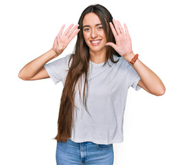 Young hispanic girl wearing casual white t shirt showing and pointing up with fingers number nine...