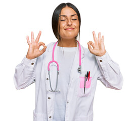 Beautiful hispanic woman wearing doctor uniform and stethoscope relax and smiling with eyes closed doing meditation gesture with fingers. yoga concept.