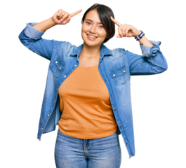 Young beautiful hispanic woman with short hair wearing casual denim jacket smiling amazed and surprised and pointing up with fingers and raised arms.