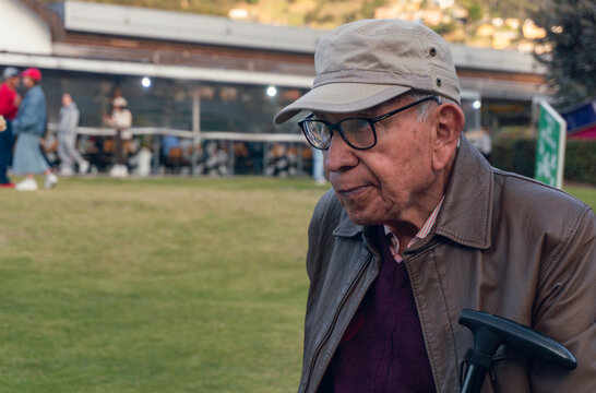 Portrait of 83 year old latino older person with serious expression and a cane in his lap looking to the side with copy space