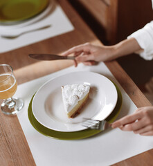Romantic Dinner at Home Smiling Woman Enjoying a Delicious Meal A beautiful brunette woman sits at a trendy dining table, surrounded by elegant decorations She looks ecstatic as she takes a bite of