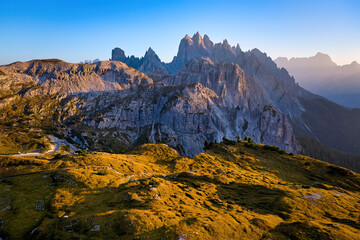 Mountain landscape and sharp Dolomites peaks lit by the setting sun around Tre Cime di Lavaredo, perfect for trekking on an autumn day. Vivid colors, orange to blue shades. UNESCO site, Italy.