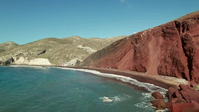 Santorini red sand beach drone fly over at daytime