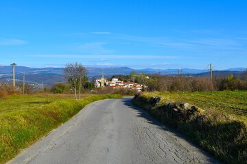 Asphalt road in Istria, Slovenia with Pomjan village and hills in the background