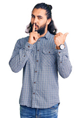 Young arab man wearing casual clothes asking to be quiet with finger on lips pointing with hand to the side. silence and secret concept.