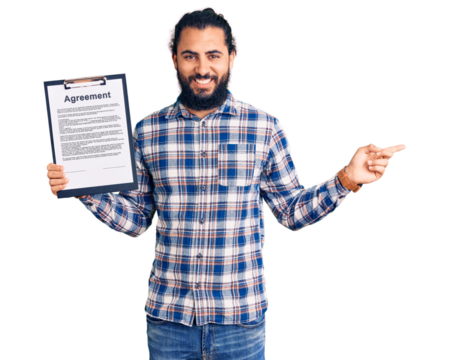 Young arab man holding clipboard with agreement document smiling happy pointing with hand and finger to the side
