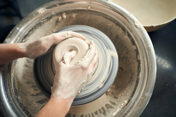 Unrecognizable female ceramics maker working with pottery wheel