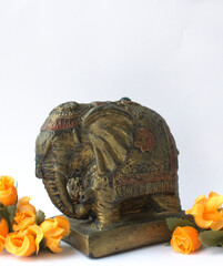Old Indian elephant statue figure home decor isolated on white background with orange color flowers and copy space on top