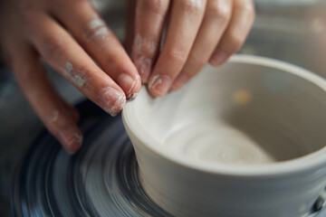 Female hands of potter making cup from clay on pottery wheel