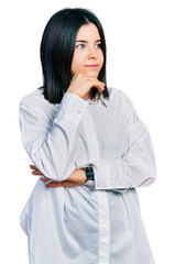 Young brunette woman with blue eyes wearing oversize white shirt with hand on chin thinking about question, pensive expression. smiling and thoughtful face. doubt concept.