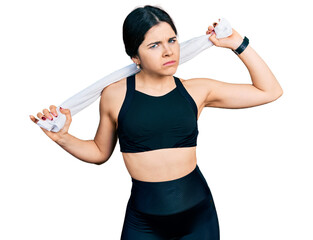 Young brunette woman with blue eyes wearing sportswear and towel clueless and confused expression....