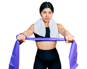 Young brunette woman with blue eyes training arm resistance with elastic arm bands skeptic and nervous, frowning upset because of problem. negative person.