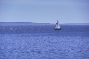 The sailboat sails calmly on the blue sea in the calm of the day