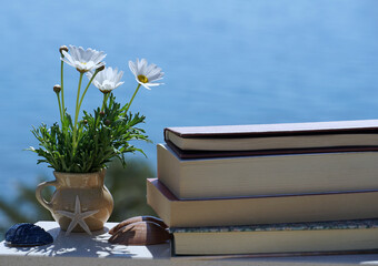 Enjoy the summer vacation memories with books, flowers and sea shells on the blue background