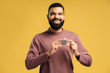 Smiling African American man holding pacemaker, cardioverter defibrillator looking at camera - obrazy, fototapety, plakaty