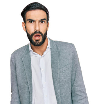 Young hispanic man wearing business clothes in shock face, looking skeptical and sarcastic, surprised with open mouth