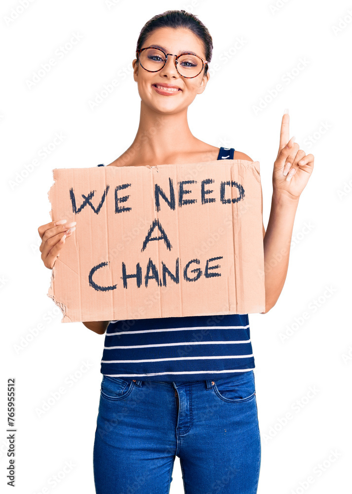 Canvas Prints Young beautiful woman holding we need a change banner surprised with an idea or question pointing finger with happy face, number one