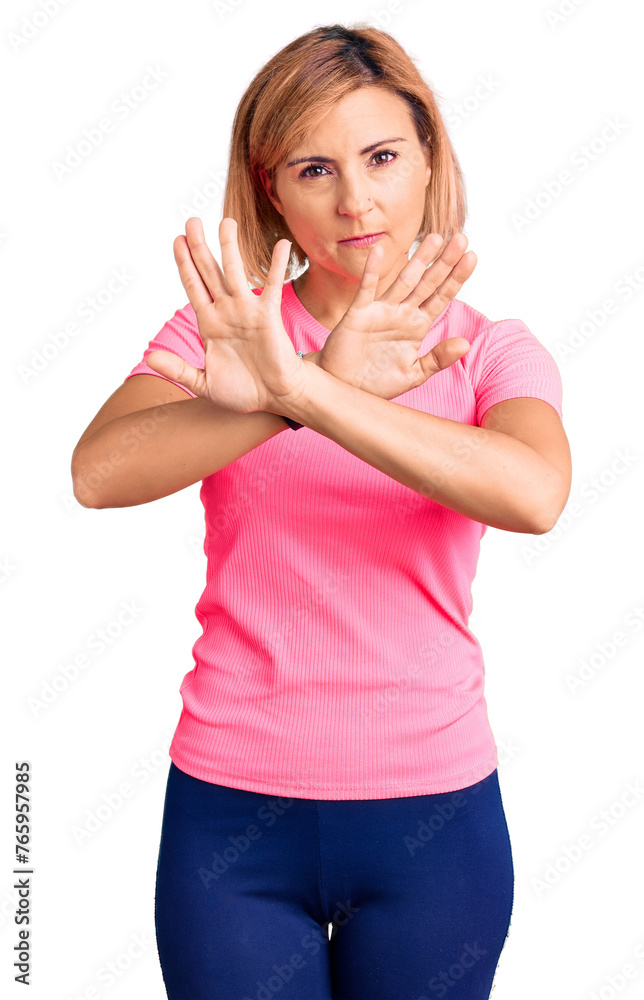 Poster young blonde woman wearing sportswear rejection expression crossing arms and palms doing negative si