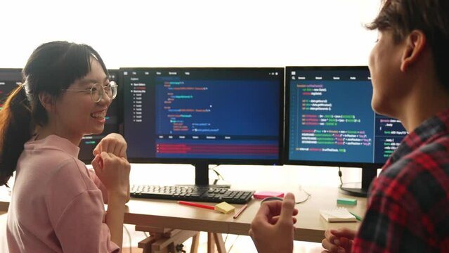 Slow motion back end software developer engineer for computer programming working together on debugging writing computing code, solving complex algorithms display on monitor in office. Burgeoning