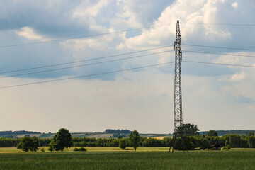 A tall power pole with high-voltage lines located in a field