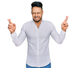 Young arab man wearing casual clothes gesturing finger crossed smiling with hope and eyes closed. luck and superstitious concept.