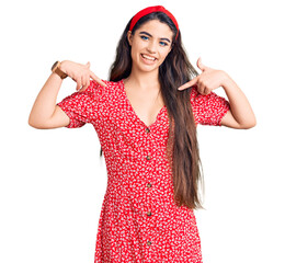 Brunette teenager girl wearing summer dress looking confident with smile on face, pointing oneself with fingers proud and happy.