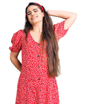 Brunette teenager girl wearing summer dress suffering of neck ache injury, touching neck with hand, muscular pain