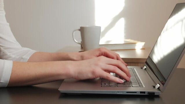 Side view on woman's hands, typing the text on laptop. 