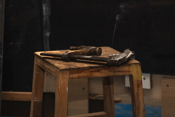 closeup Vintage Carpenter's Clamp with Smoking Cigarette on Wooden Workbench in Carpentry Workshop