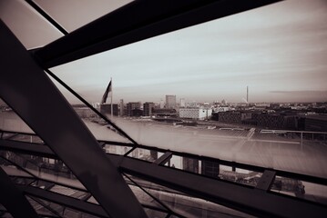 Monochrome cityscape viewed through geometric window frames, showcasing urban architecture under a hazy sky.