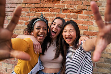 Portrait three excited multiracial joyful girls outdoors. Young females having fun posing for photo...
