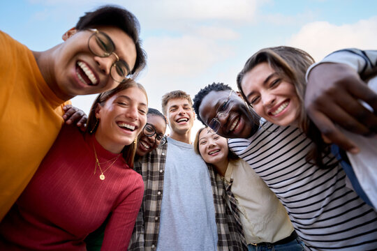 Portrait large group multiracial friends posing smiling and looking to camera. Happy young people hugging together standing outdoors. Photo of generation z guys and girls enjoying spring vacation day