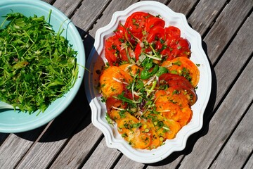 View of a colorful heirloom tomato slice salad with fresh herbs on a platter in Provence, France - 765993593