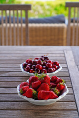 Bowl of fresh cherries and bowl of fresh strawberries in summer - 765993915
