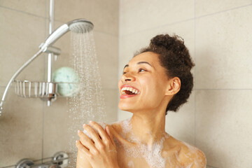 A woman in the shower, smiling and enjoying the water from the plumbing fixture