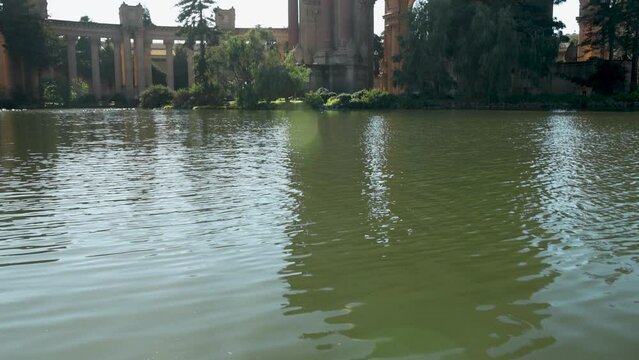 titl footage of a beautiful spring landscape at Palace of Fine Arts with a lake, lush green trees and plants and beautiful buildings with blue sky in San Francisco California USA