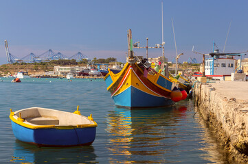 Multi-colored fishing boats luzzi with eyes in the harbor of the village Marsaxlokk on the island Malta. - 766002174