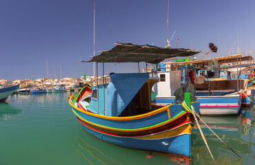 Multi-colored fishing boats luzzi with eyes in the harbor of the village Marsaxlokk on the island Malta. - 766002355