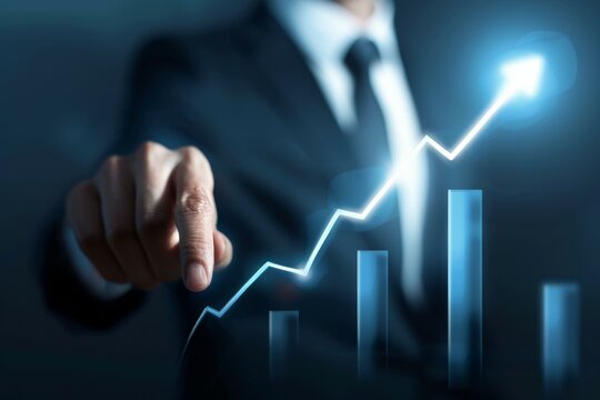 A man in a suit is pointing at a graph with a rising line